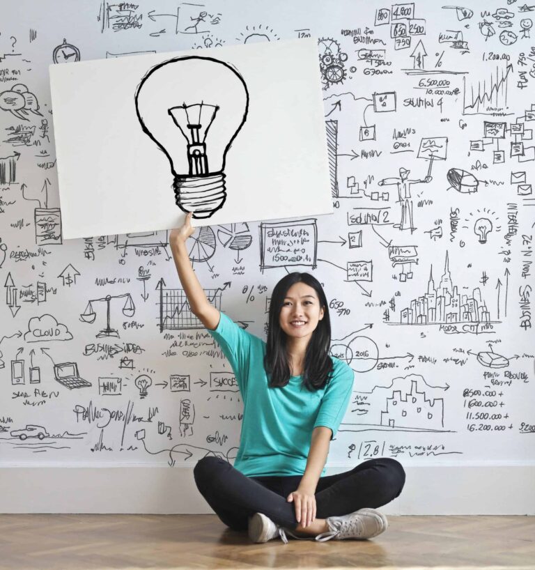 A woman holding up a large white sign with a lightbulb. Discover the difference between a CE & a CEU by exploring our blog. Get started with our continuing education online courses today.