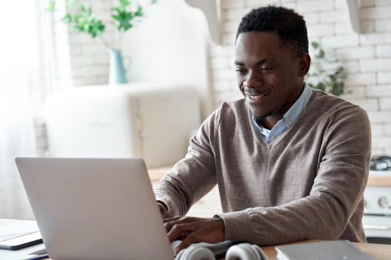 A business professional man sitting down smiling while typing on his laptop. Did you know that online continuing education doesn't have to be a snooze fest? Read our blog here on why professional development is important.