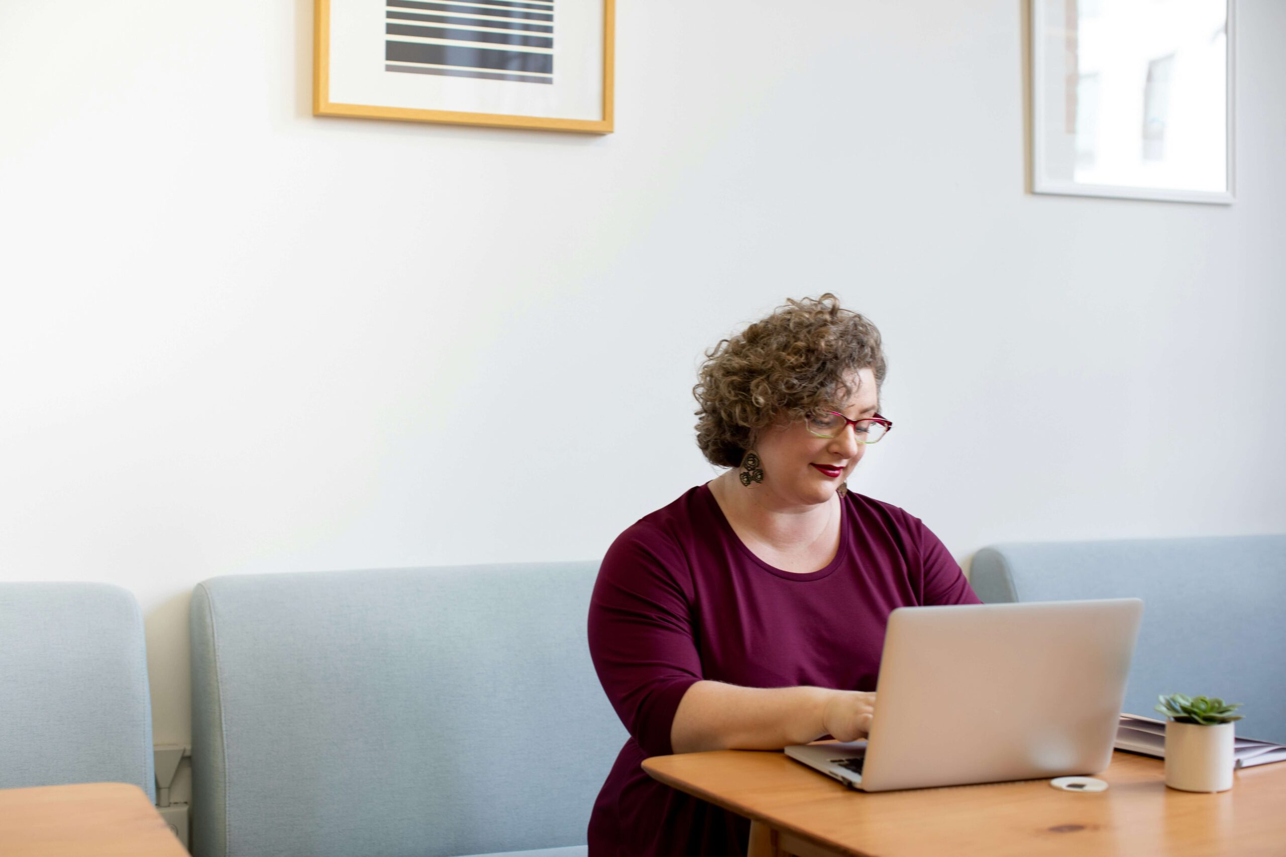 A woman typing on her laptop while sitting down at a booth. If you want to learn how our online continuing education for therapists can help you, reach out to us today! Our instructors would love to help support your continuing education journey.