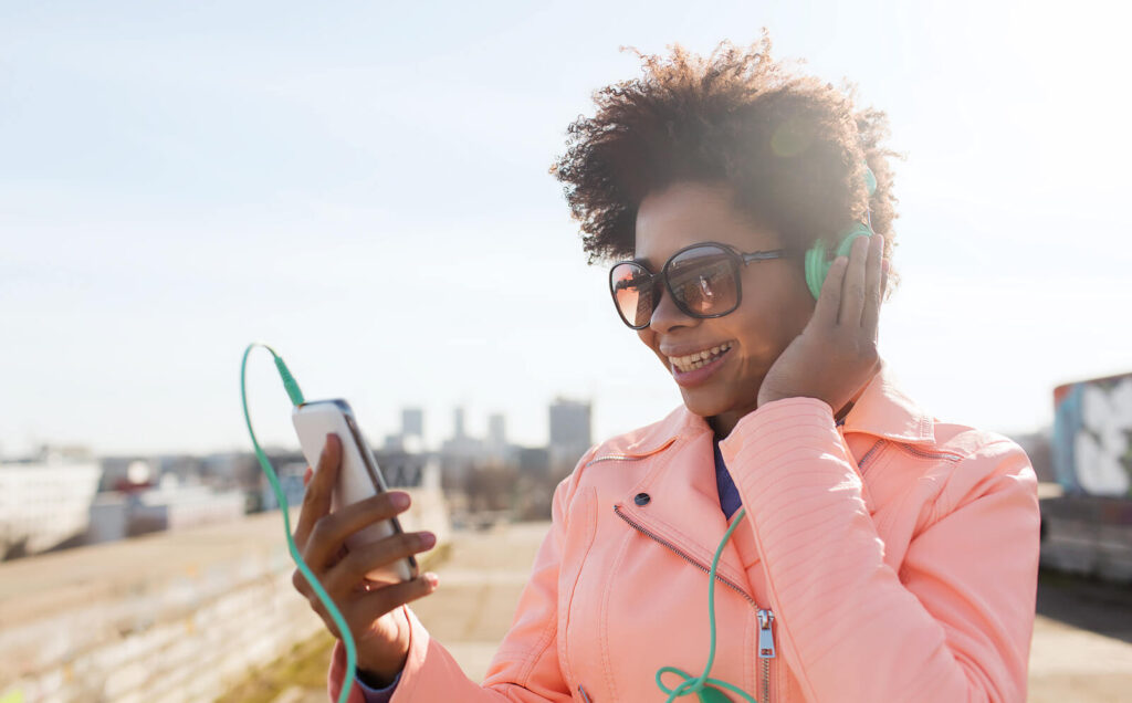 woman wearing green headphones | ceus for counselors | ceu credits for counselors | online ceus for counselors | Nevada | New York | Arizona A woman holding her headphones closer to her ears while holding her phone up to see. Our continuing education for counselors can be done at home or on the go. Read our blog here to discover how to obtain your CEs in different states.