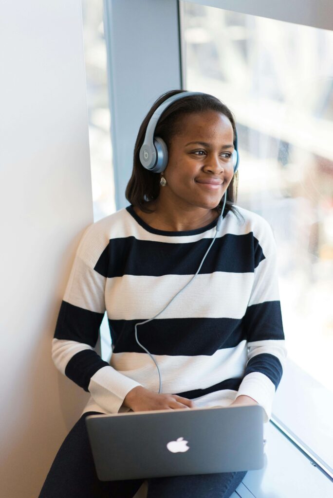 A woman sitting in a window sill wearing headphones & typing on a laptop. Our online continuing education courses can help you learn more about OCD & the symptoms. Get started with our courses today!